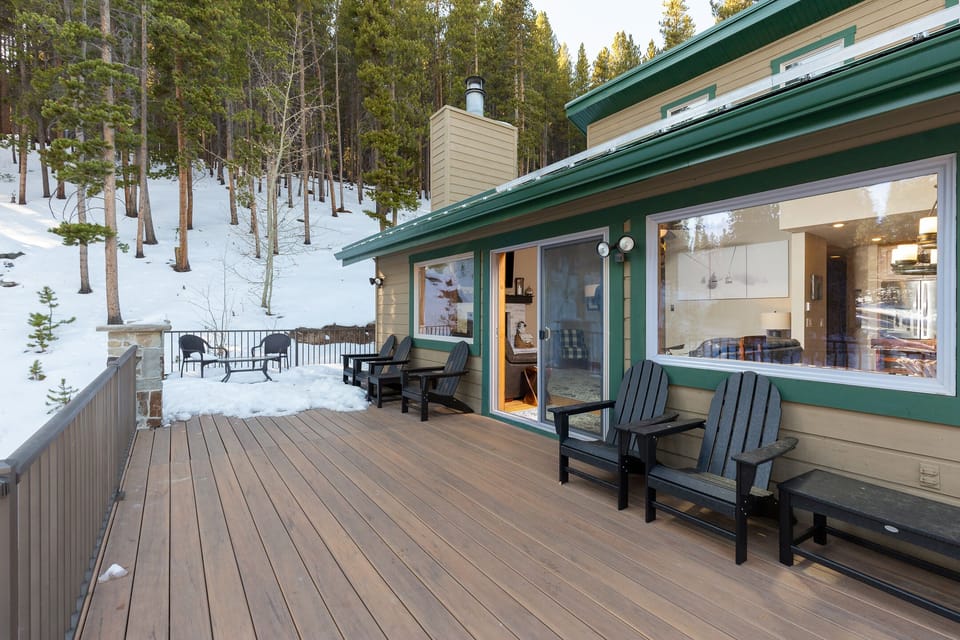 Step onto your private deck overlooking a pristine winter forest, where warm Adirondack chairs await cozy evening moments.