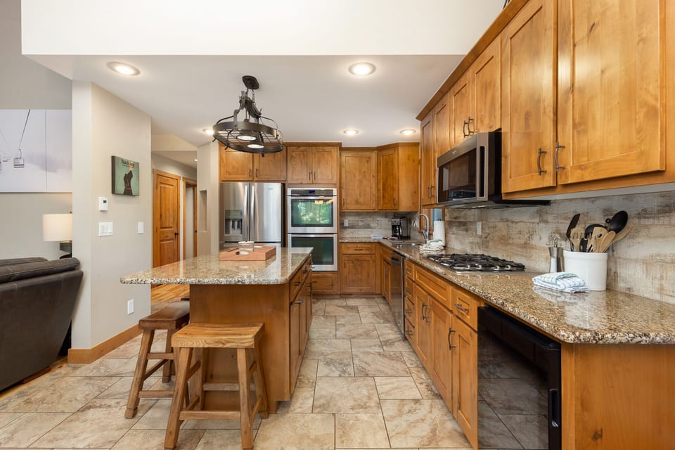 Your spacious kitchen awaits with warm wood cabinetry, granite countertops, and modern appliances for preparing memorable meals together.