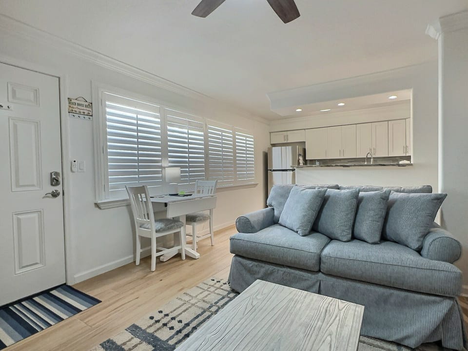 Open living space with sofa, entry door, and ceiling fan