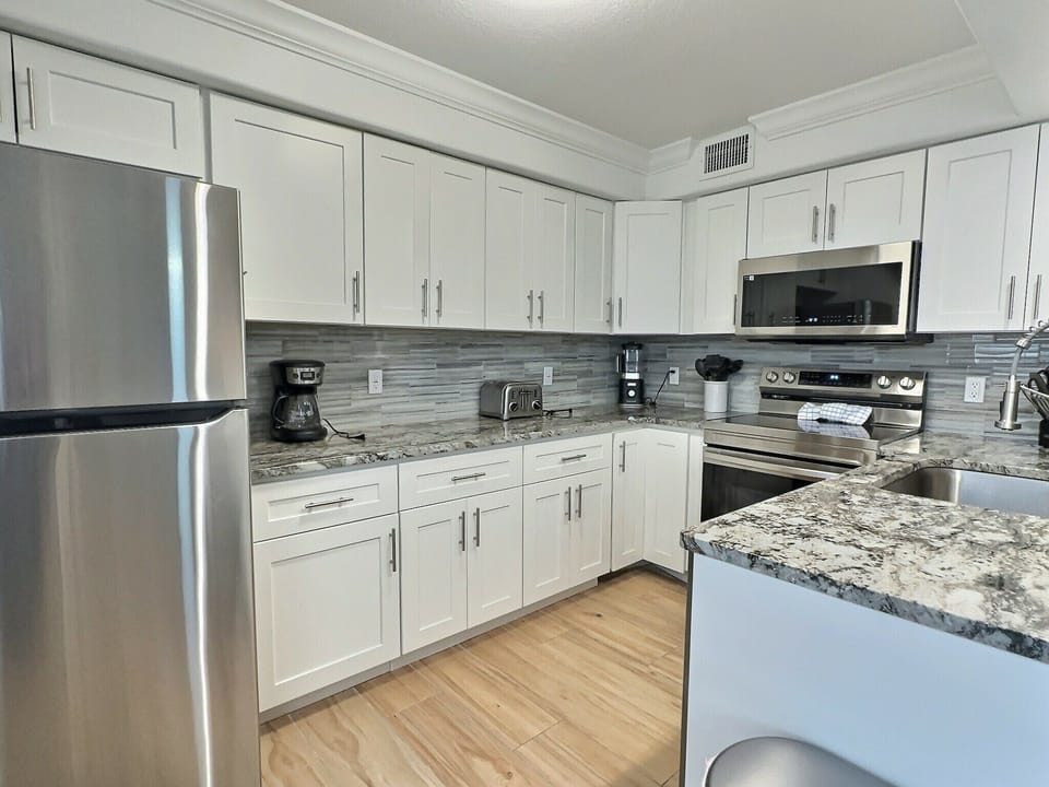 Kitchen with white cabinets, stainless appliances, and stone countertops