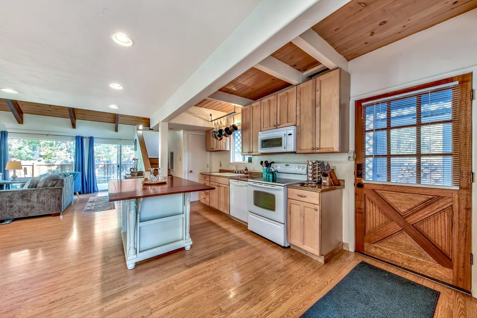 Kitchen area with honey-toned cabinets, white appliances, a butcher block island, and a wooden back door with glass panes.