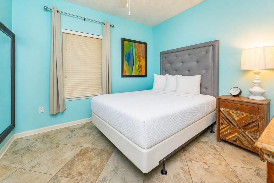 Queen bed in the guest suite invites you to unwind beneath calming blue walls and gentle lamp light