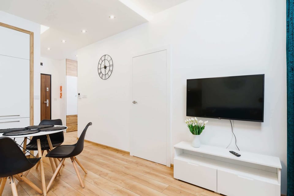 A view of the dining area connected to the living space. It includes a round table with black chairs and a television mounted on the wall.