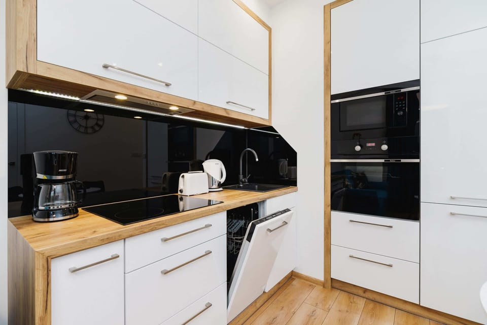 A compact and modern kitchenette with white cabinets and a sleek black countertop. Built-in appliances are neatly integrated.