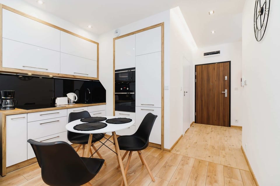 A view of the dining area connected to the living space. It includes a round table with black chairs and a television mounted on the wall.