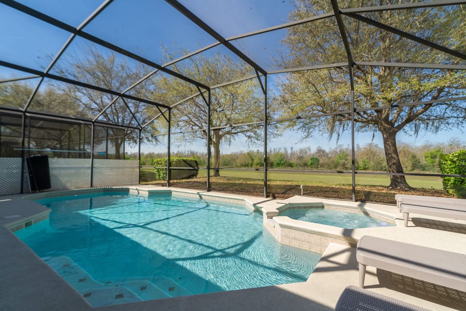 Screened private pool and spa with conservation view and poolside seating.