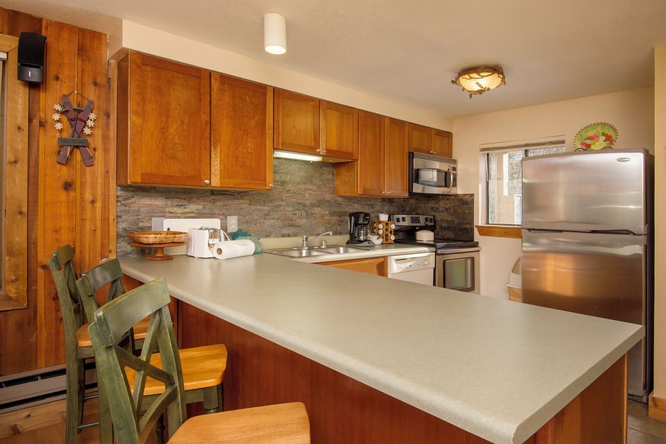 Your fully equipped kitchen features warm wood cabinets, stainless steel appliances, and a breakfast bar perfect for morning coffee or casual meals.