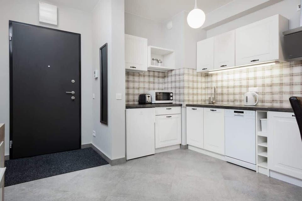 A compact and functional kitchenette with white cabinets, tiled backsplash, and a well-organized countertop space.