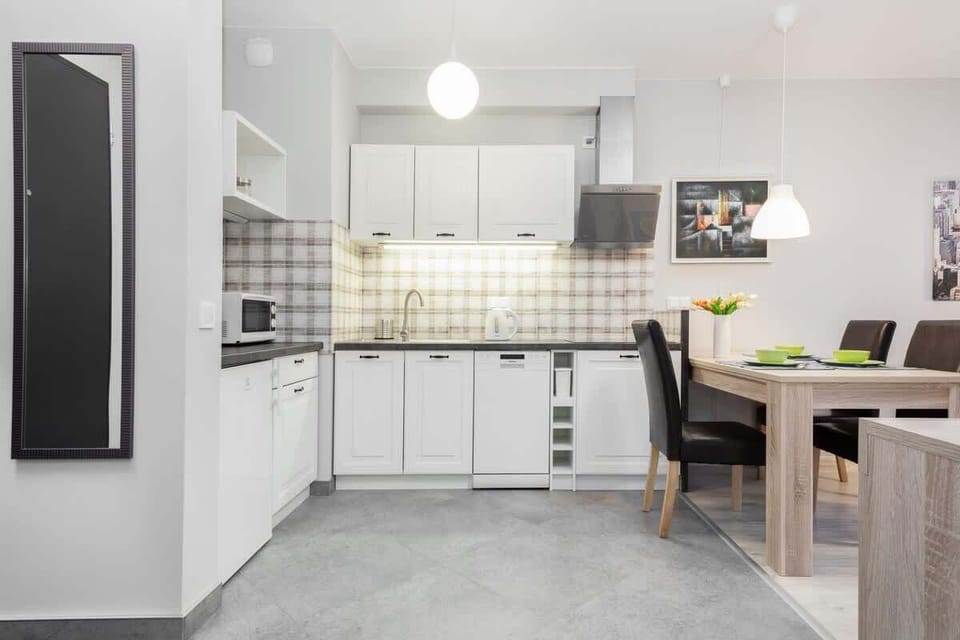 A compact and functional kitchenette with white cabinets, tiled backsplash, and a well-organized countertop space.