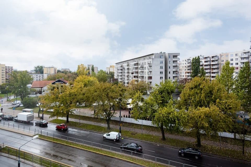 A view of the street from the apartment, showing cars, trees, and surrounding buildings, creating an urban neighborhood vibe.
