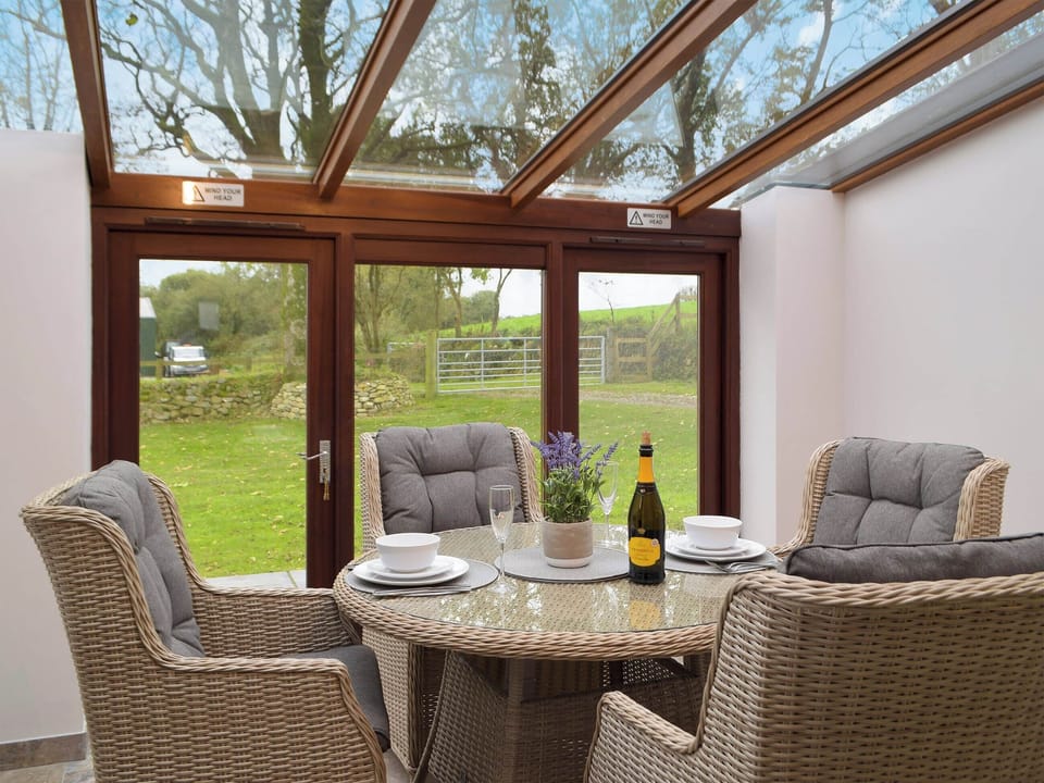 Sun room/dining area with patio doors leading to garden | Snowdrop Cottage - Penfeidr Cottages, Glanrhyd, near Newport