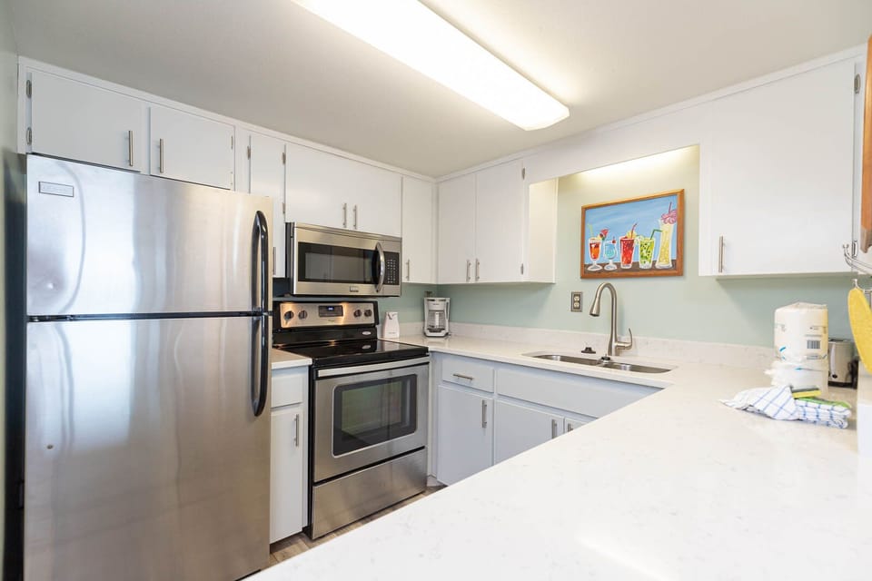 This kitchen features stainless steel appliances, white cabinetry, and a bright countertop, perfect for meal preparation