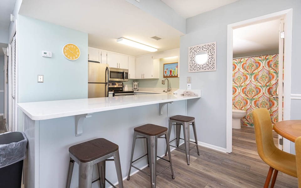 This kitchen features stainless appliances, a bright countertop, and a cozy bar area with stylish stools for casual dining