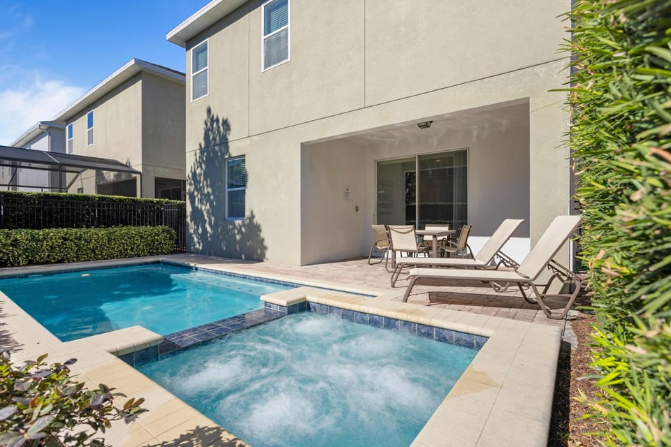Sunlit private pool and spa with ample lounging space in a serene backyard, perfect for relaxation.