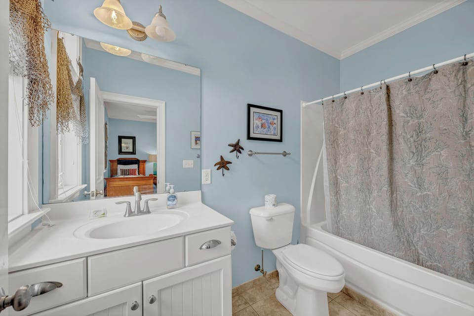 A coastal-themed bathroom awaits you, featuring soft blue walls, charming seaside décor, and a spacious vanity with crisp white countertops. Slip into a refreshing shower surrounded by beach-inspired touches.