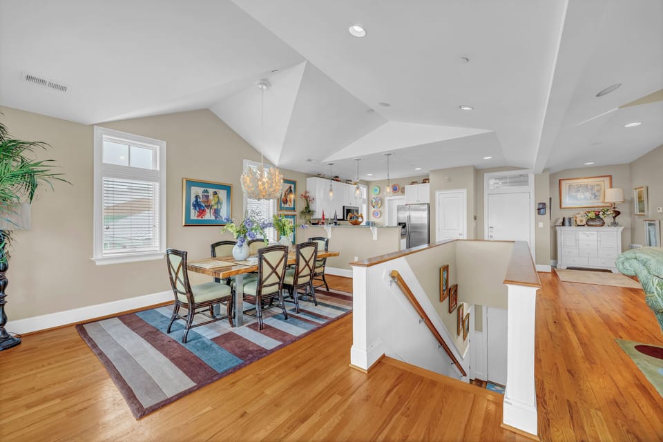 Bright, airy dining and kitchen space with vaulted ceilings and gleaming hardwood floors welcomes you home. Share meals at the inviting dining table under stylish pendant lighting, or unwind on the cozy seating area with colorful artwork adding warmth thro