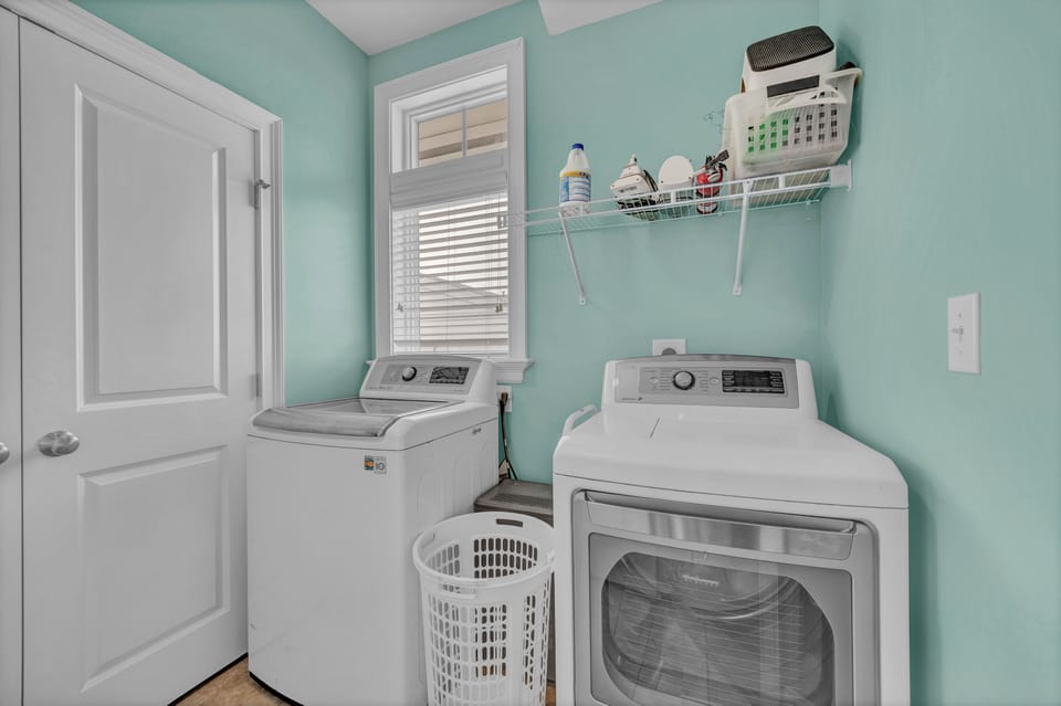 Your private laundry room features full-size washer and dryer, shelving for supplies, and natural light from a window—making it easy to keep fresh during your stay.