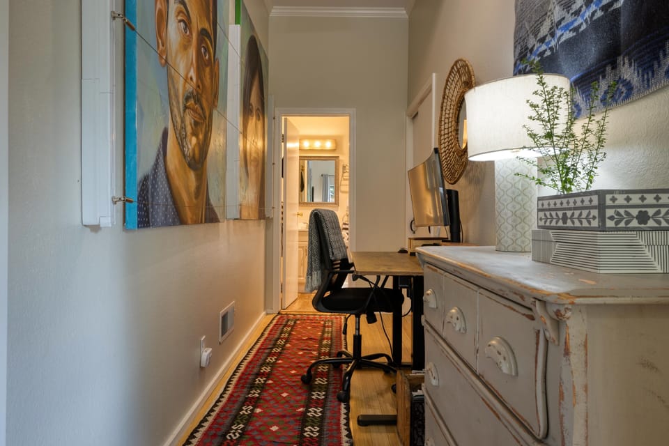 Downstairs, a hall between bedroom and bathroom ~ lined with original art - like a personal art gallery and a dedicated workspace.