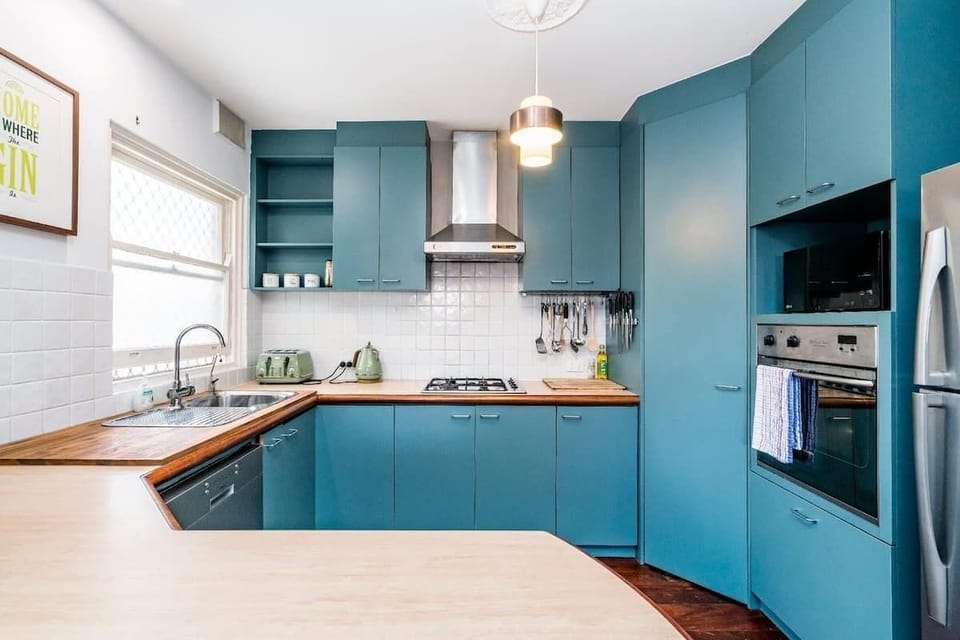 Whip up delicious meals in this bright and modern kitchen, featuring stylish blue cabinetry and all the essential appliances you need.