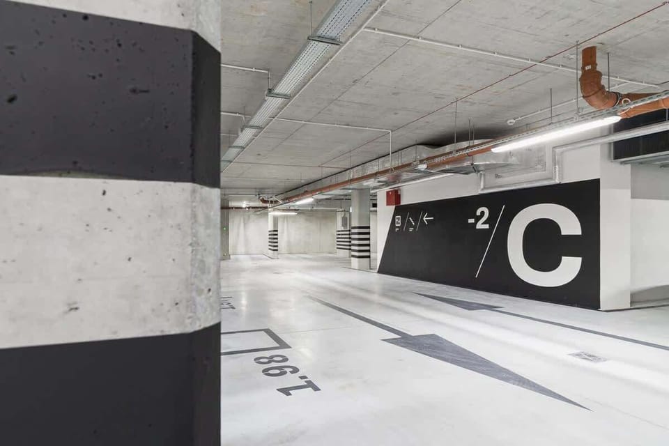 An underground parking garage with marked columns and spaces. The area is well-lit and organized, offering secure parking for residents.