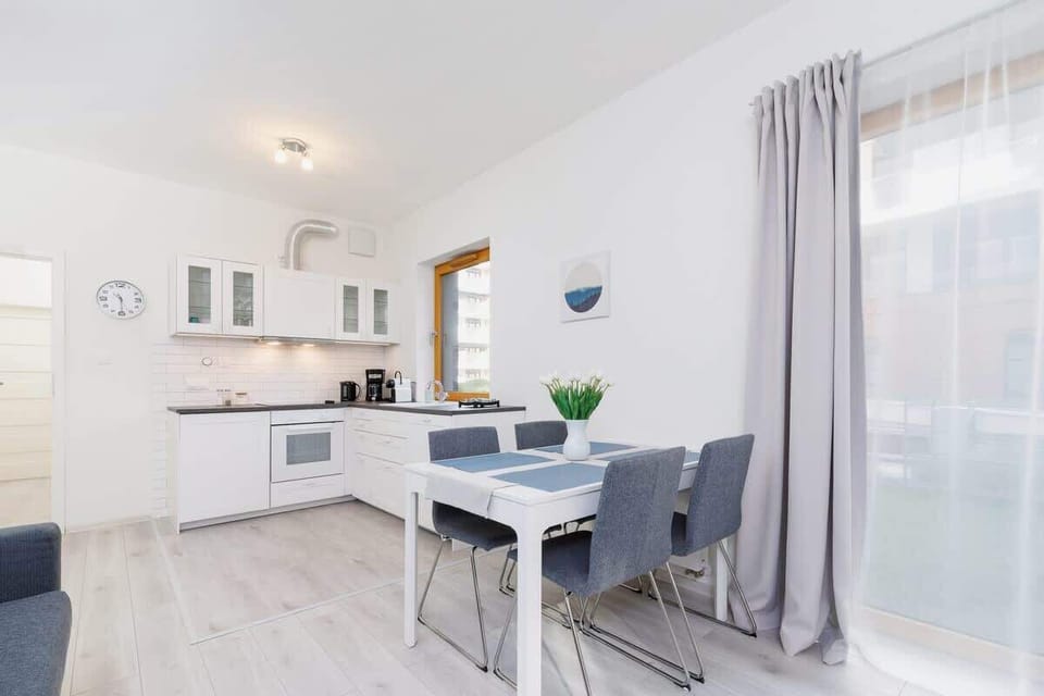  A cozy dining space with a small white table and chairs, positioned next to a large window for plenty of natural light.