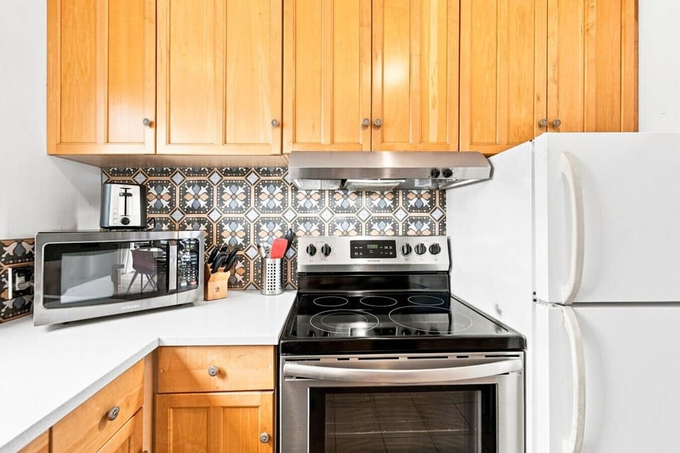 Equipped kitchen 🍳 Full-size fridge, electric range, microwave, and custom tile.