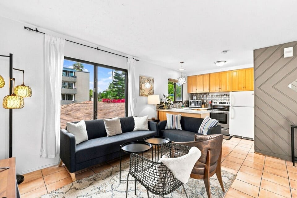 ndoor-outdoor coastal living 🌿 Spacious seating area opening directly onto a private balcony through large sliding glass doors.