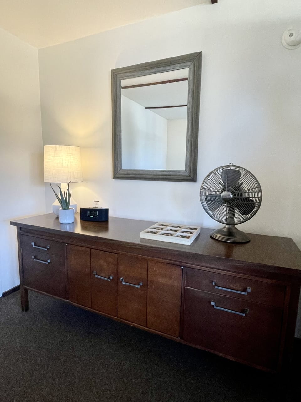 Twin bedroom with fan, alarm, luggage rack and lamps.