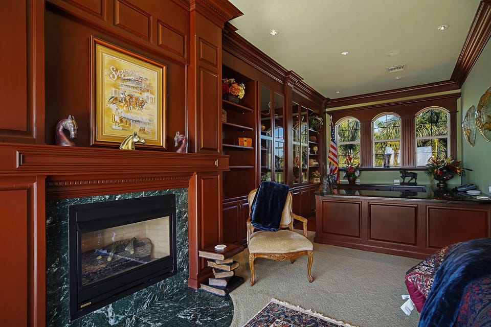 A fireplace, built-in bookshelves, and a private desk setup make this suite feel more like a personal sanctuary than a guest room.