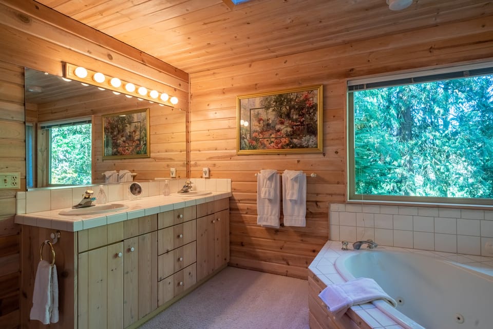 Master Bathroom - bathroom with dual sinks, Jacuzzi tub, shower, walk in closets, and views of the wooded area behind the home.