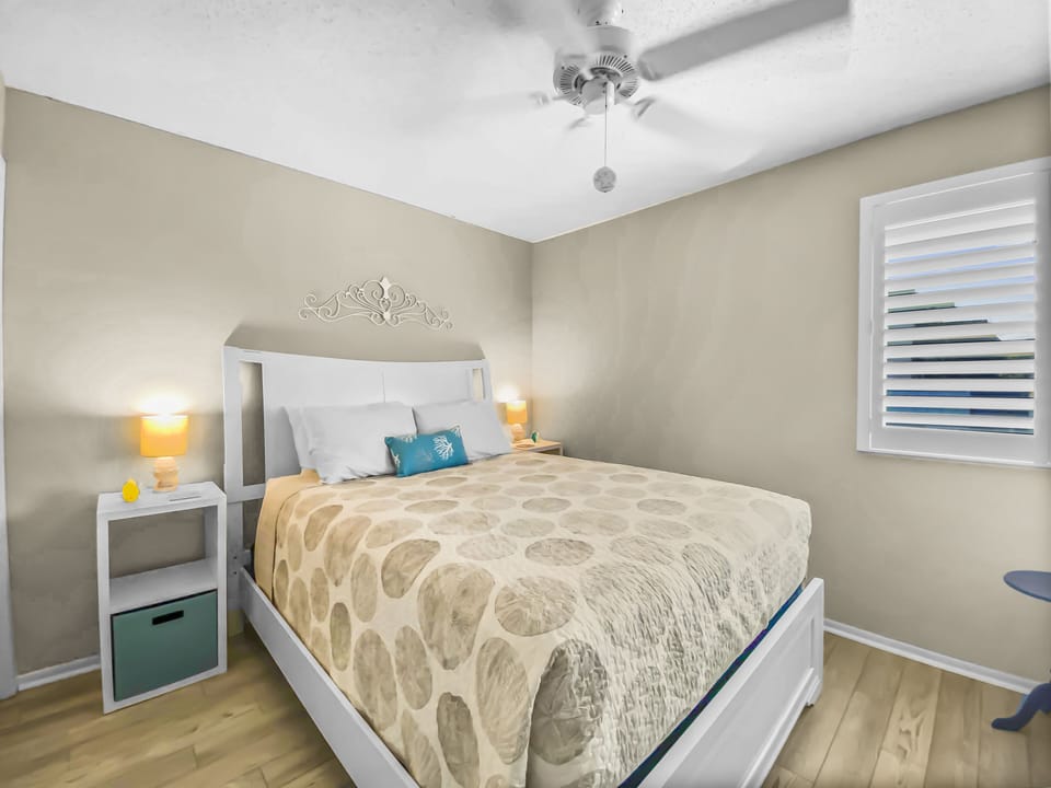 Bedroom with bed, nightstand, ceiling fan, and plantation shutters on windows