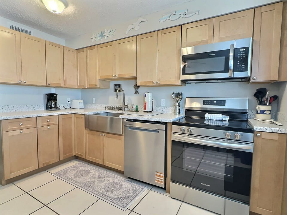 Kitchen with light wood cabinets, stainless range, and built-in microwave