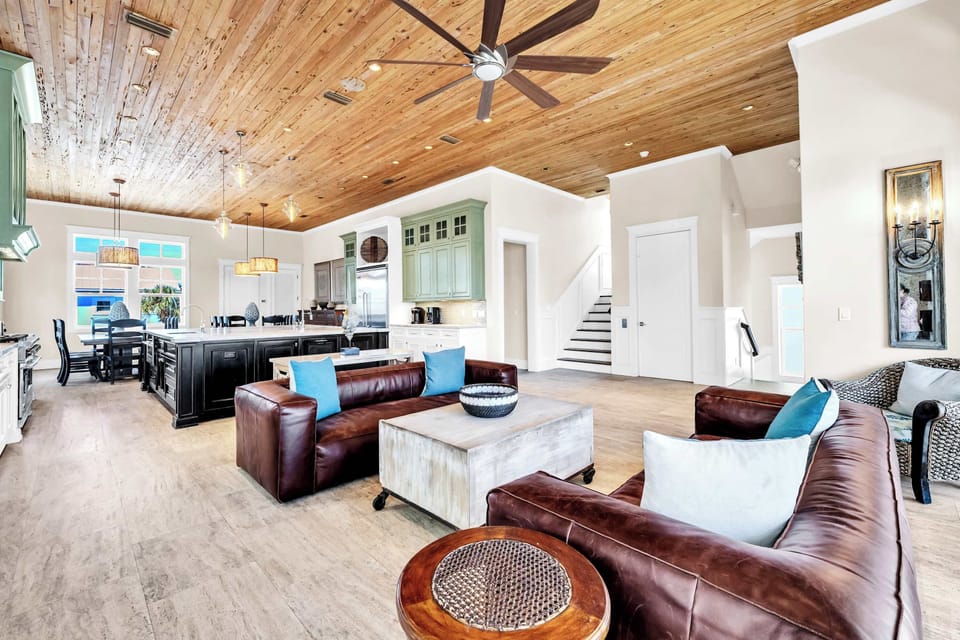 The Open Floor Plan Main Living Area Features Two Stunning Chestnut Leather Couches With Patio Access