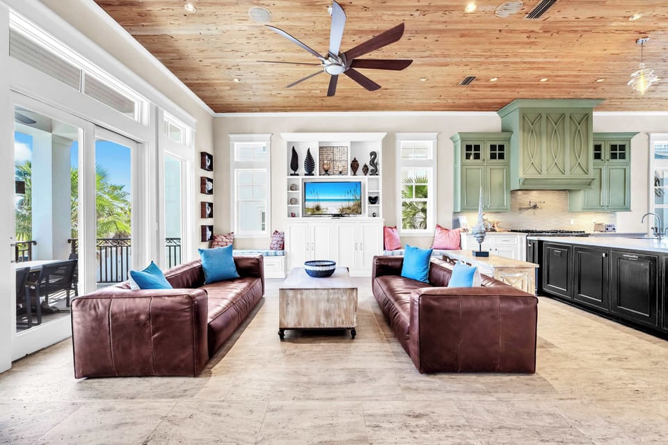 The Open Floor Plan Main Living Area Features Two Stunning Chestnut Leather Couches With Patio Access