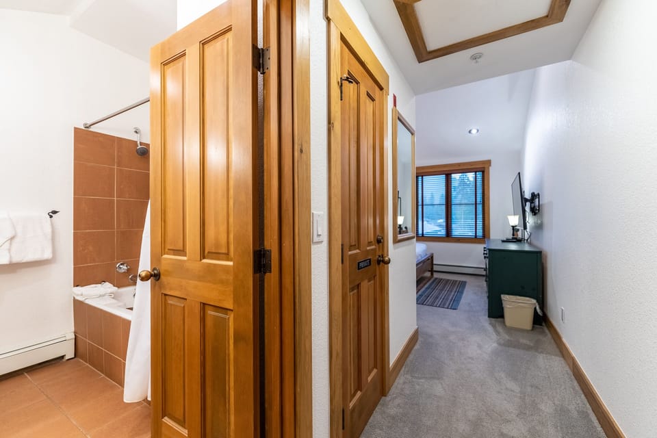 Your private bathroom features warm wood details and a relaxing tub, while exposed beams add rustic charm throughout your cozy retreat.