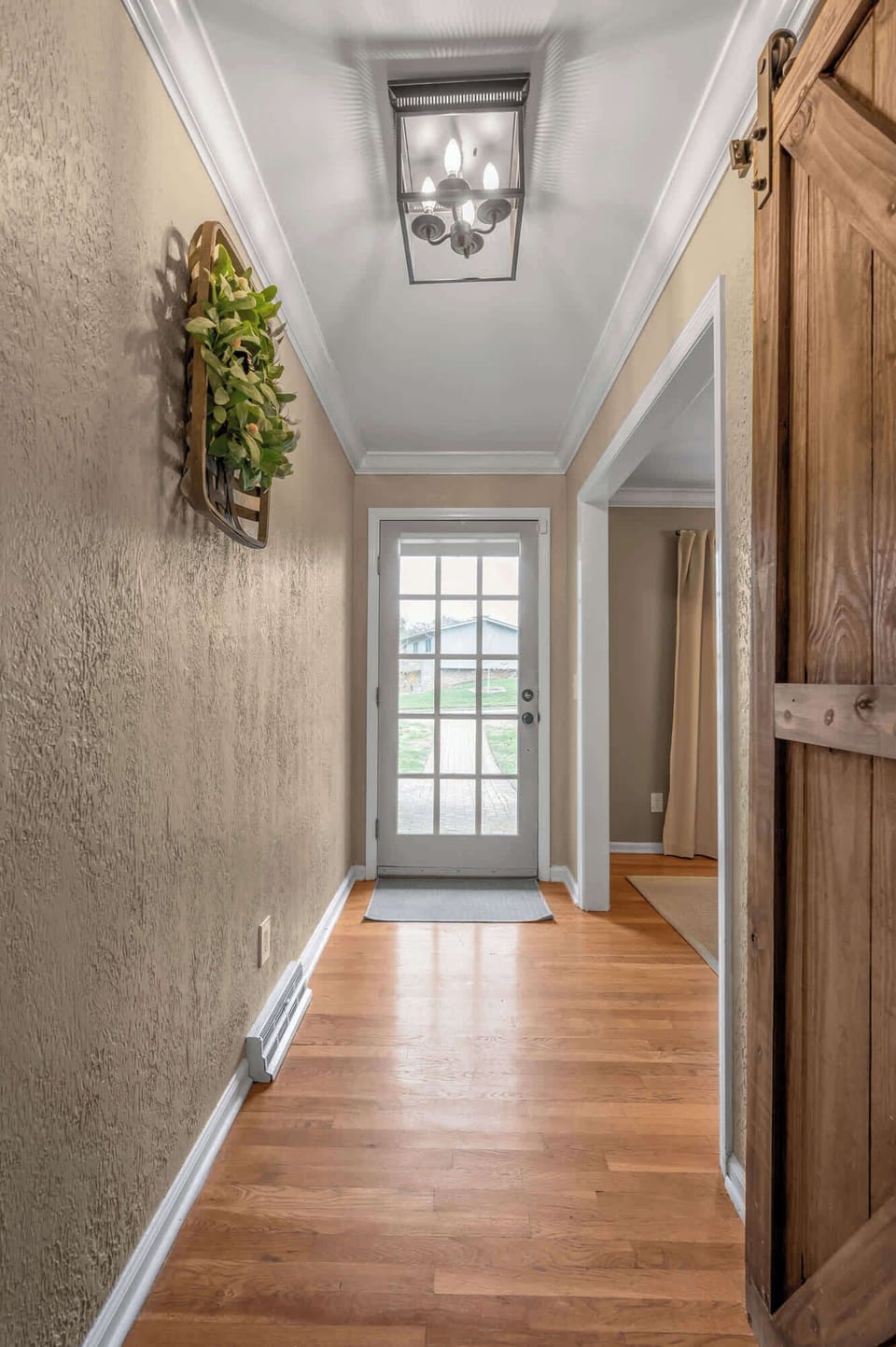 A clean, airy corridor with warm flooring and natural light guiding you toward the rear entry, offering a simple yet tasteful transition through the home.