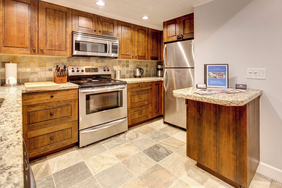Open kitchen with granite countertops, stainless appliances, new cookware 