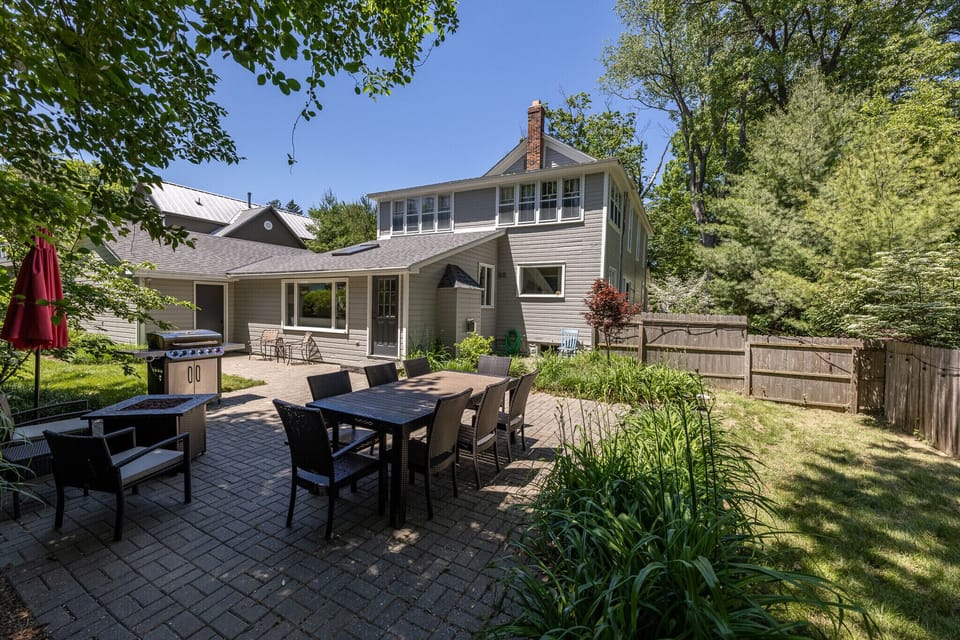 Dining table, gas firepit, gas grill, grassy play area within fenced-in yard
