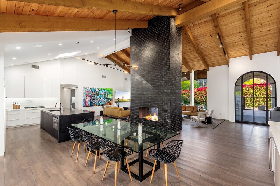 Modern desert comfort. Gather around the fireplace under soaring wood-beamed ceilings in this designer living space made for connection.