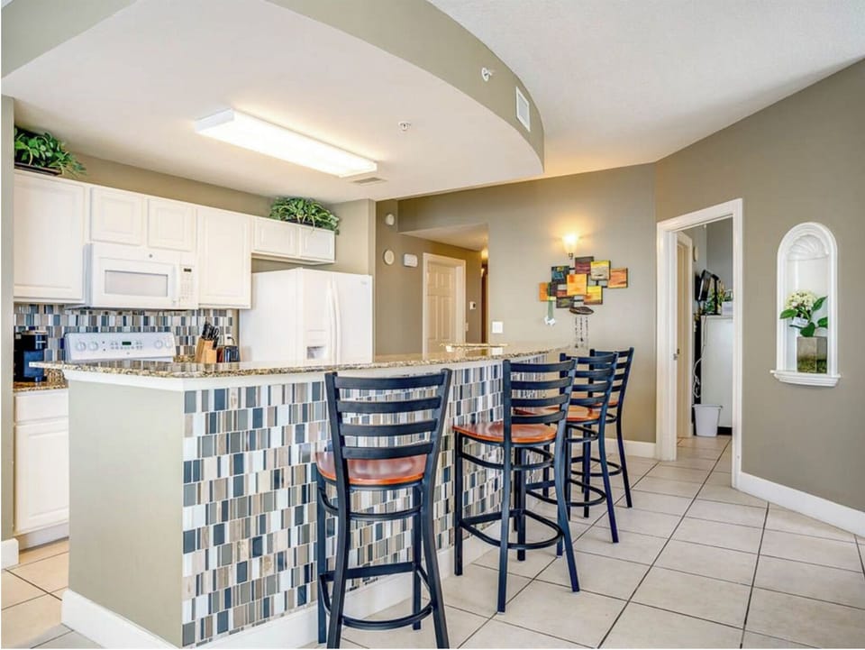 Your modern kitchen features white cabinets, granite counters, and a stylish tile backsplash with bar seating perfect for morning coffee or casual dining.