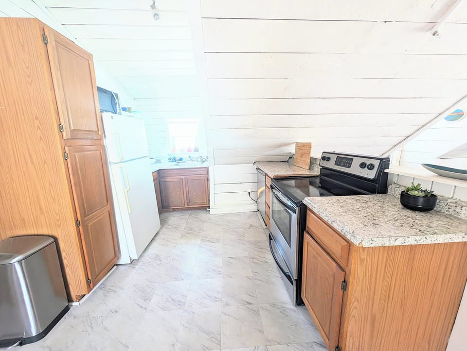 Full kitchen equipped with pots, pans, blender, baking sheets, cooking utensils.
