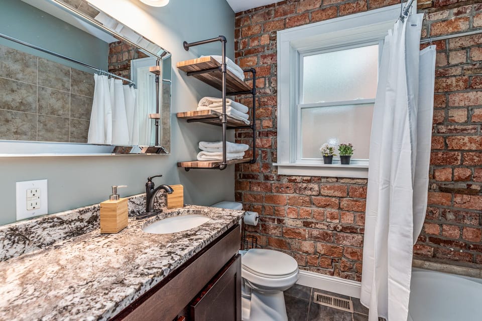 1st FLR bathroom - granite counter, exposed brick, lots of towels, bath/shower