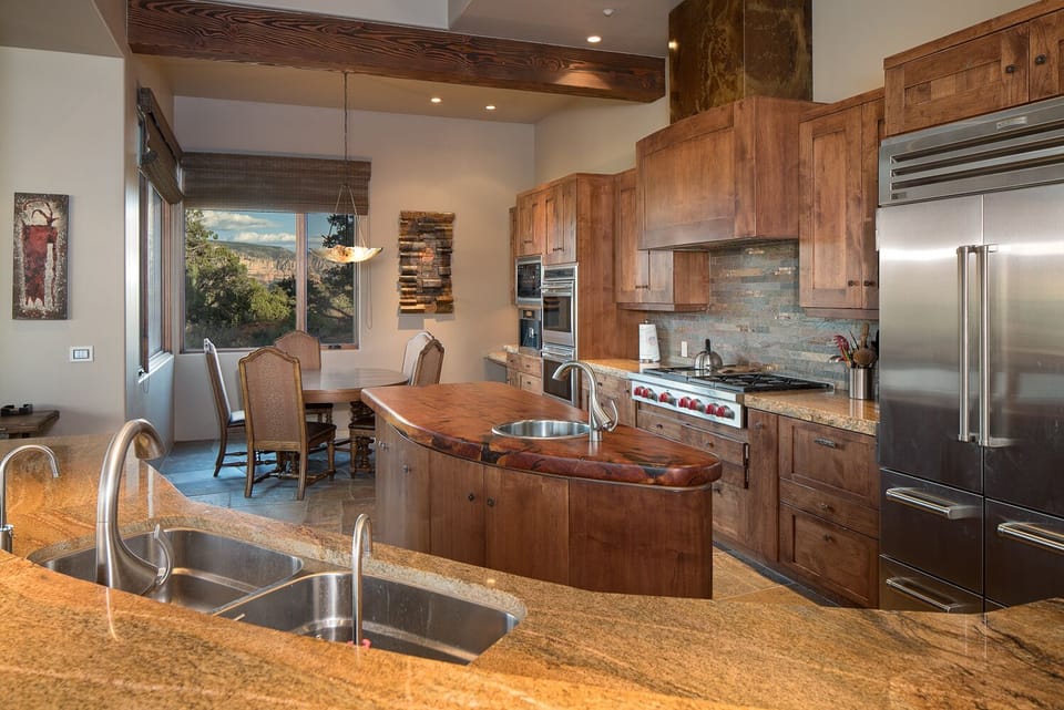 The modern chefs kitchen has Sub Zero, Viking and Dacor appliance with a dining table for 6