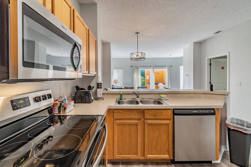 Welcome to a well-equipped kitchen featuring warm wooden cabinets and stainless steel appliances, where natural light pours in from the windows, creating a bright atmosphere perfect for your culinary adventures.