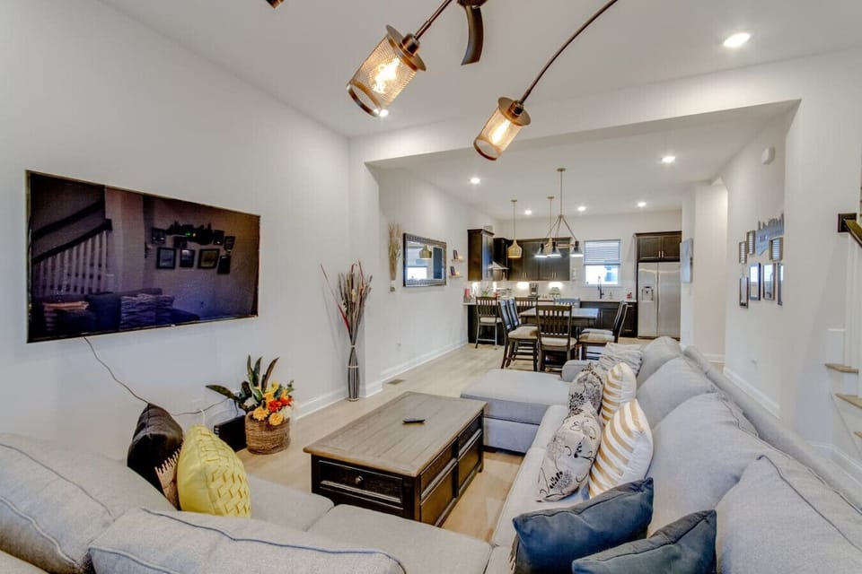 Spacious open-plan living room with sofa seating, large TV and kitchen bar