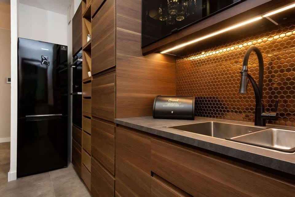 A closer look at the kitchen workspace, highlighting a sleek black sink, backsplash, and ample wooden counter space.