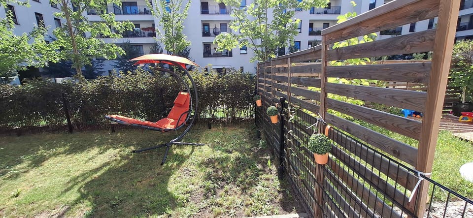 A cozy garden with a comfortable lounger and decorative fencing is a perfect spot to relax outdoors, surrounded by greenery and tranquility.