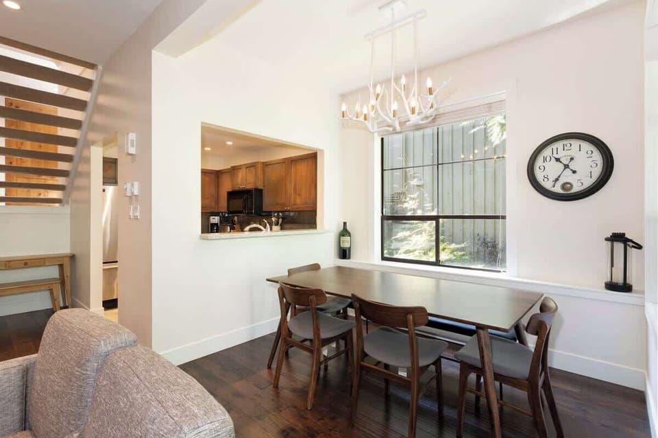 - Dining area with elegant chandelier and wood table  
- Open window bringing in forest views and natural light  
- Perfect for shared meals and Whistler getaway memories  