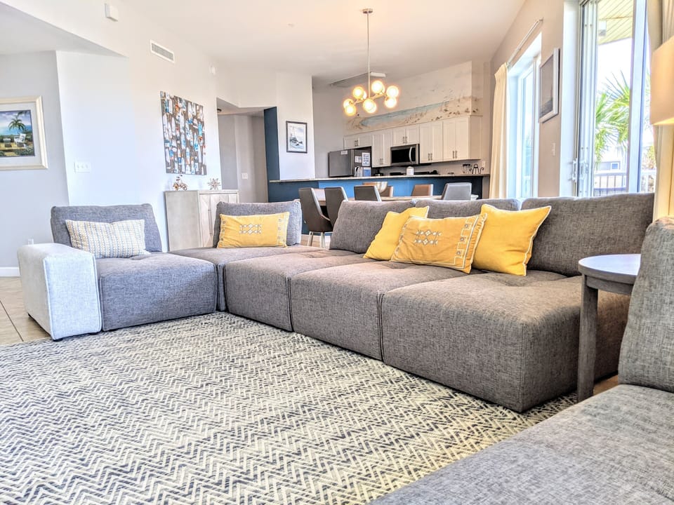 Gulf-View Living Room – Featuring a 60" TV and sectional sofa, Balcony Access