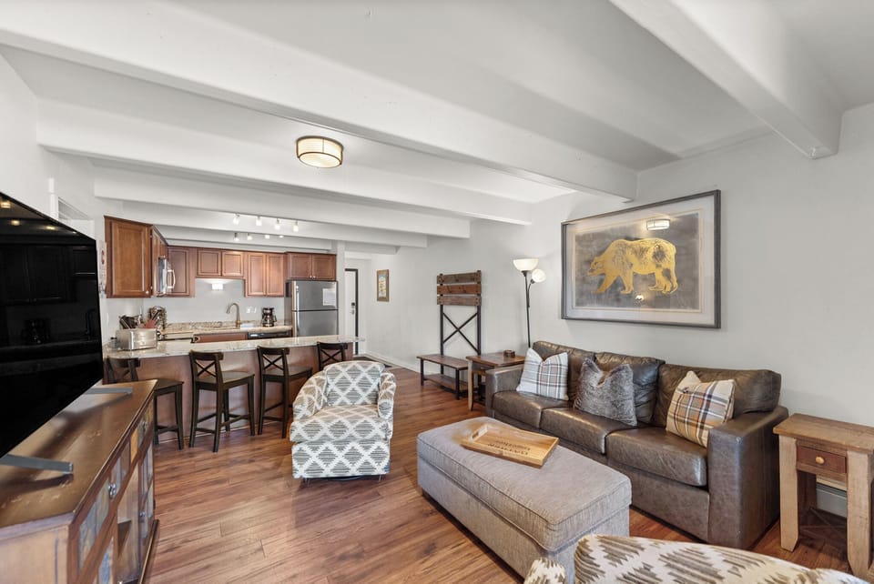 Unwind in your cozy living space featuring exposed beams, warm wood floors, and a fully equipped kitchen perfect for home-cooked meals.